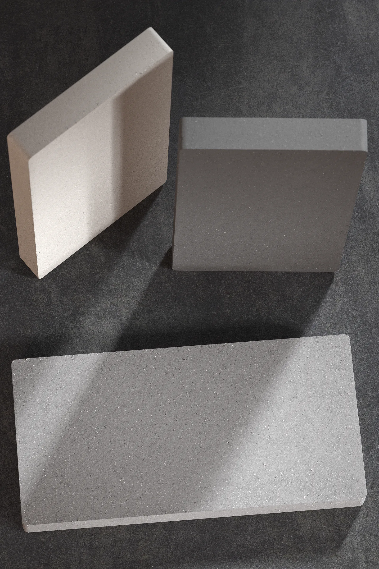 Détail du profil et de la texture du pavé en béton monocouche de la collection Bloque en blanc, gris et noir